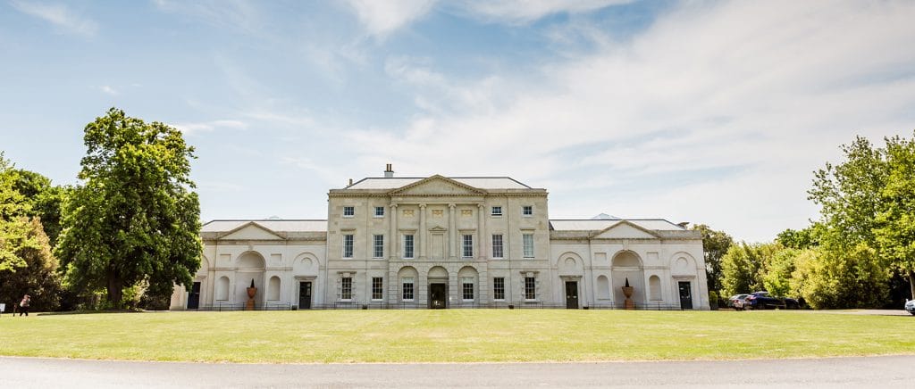 The front view of Cams Hall with driveway and lawn on a summers day.