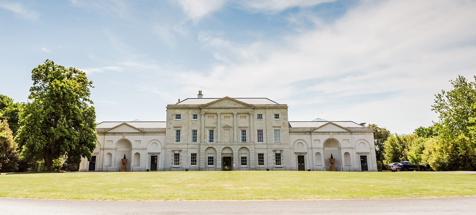 The front view of Cams Hall with driveway and lawn on a summers day.